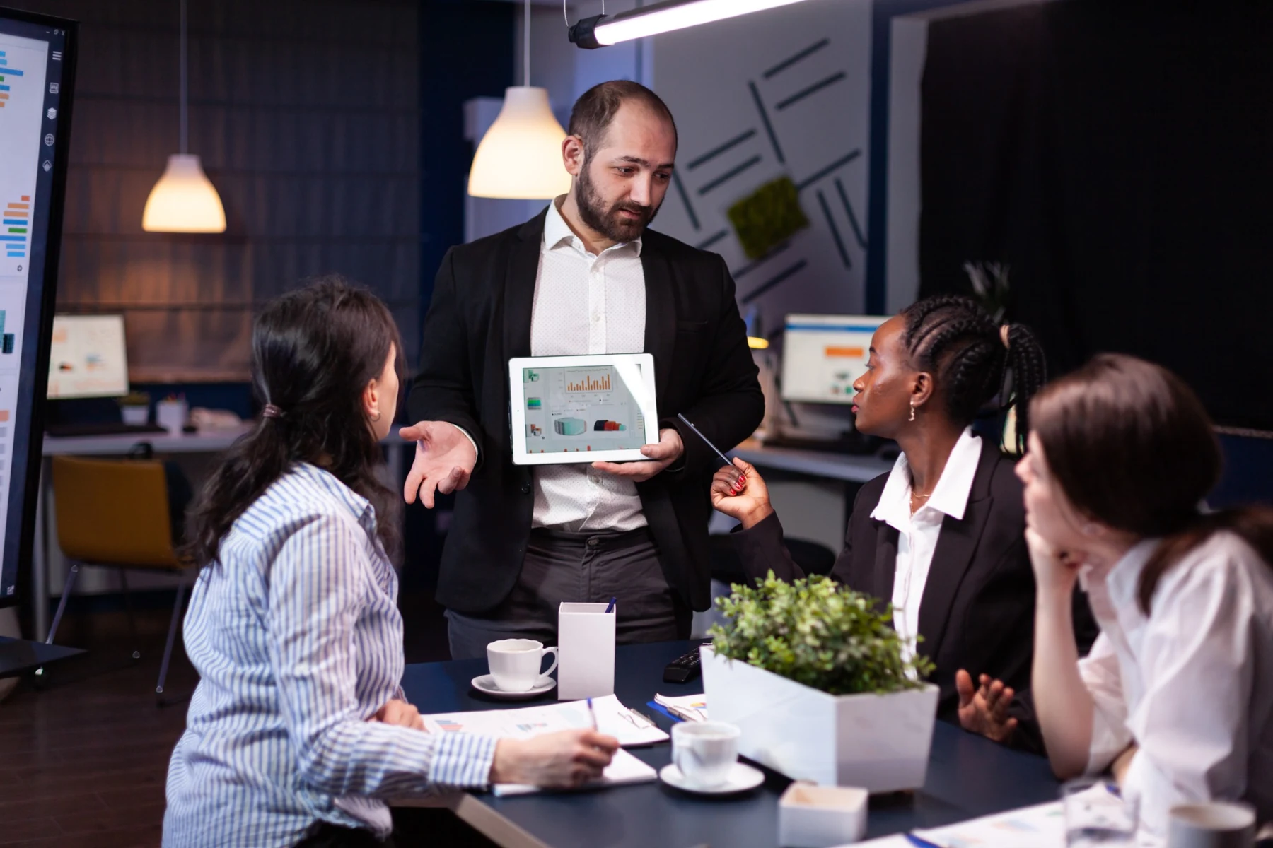 A business team discussing graphs and ideas around a tablet