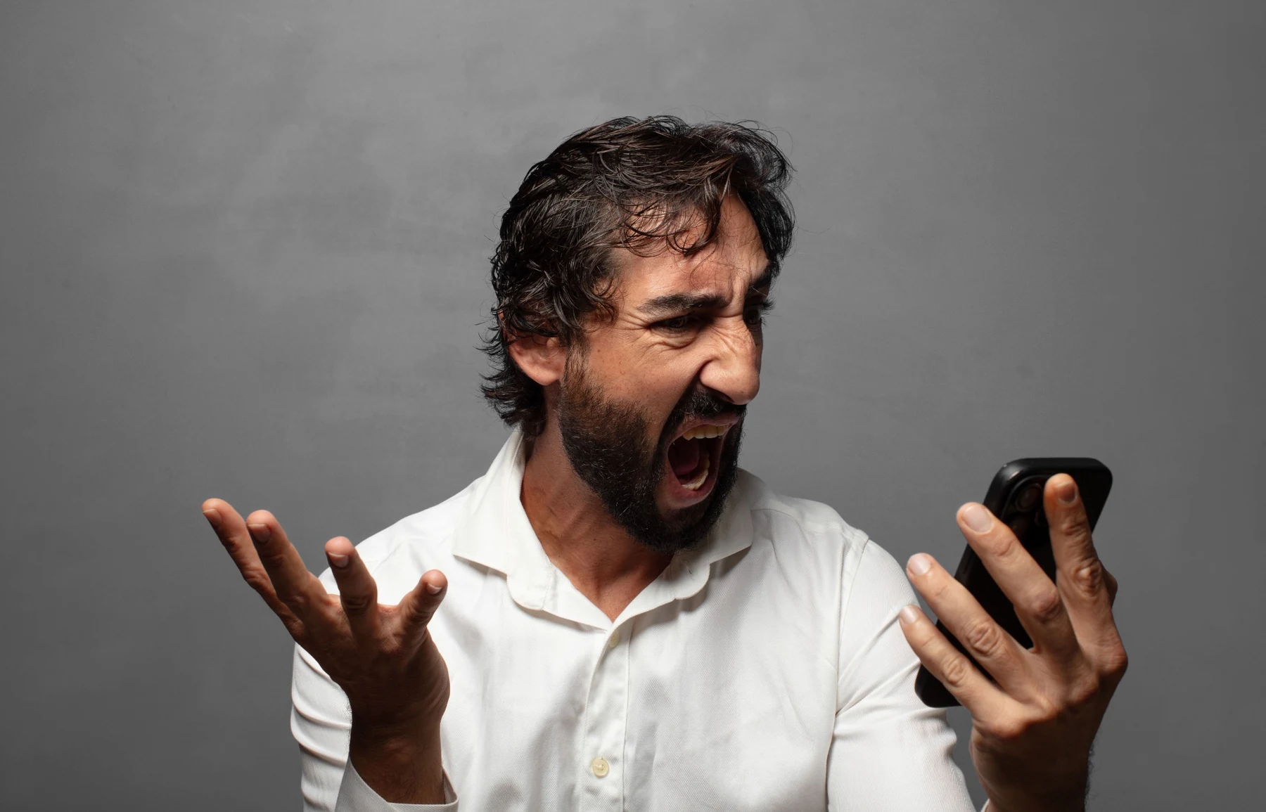 A man frustrated with a smartphone while trying to get work done